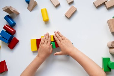 Çocuk eller beyaz yüzeyde renkli tahta bloklarla oynuyorlar. Yüksek kalite.