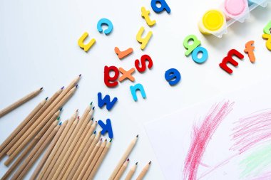 Renkli alfabe harfleri ve beyaz arka planda renkli kalemler. Yüksek kalite.