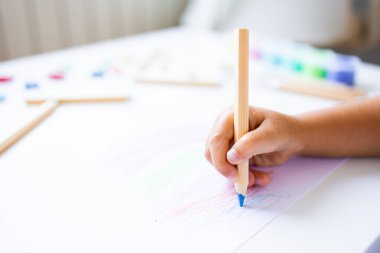 Beyaz kağıda renkli kalemler çizen küçük bir çocuk. Yüksek kalite.