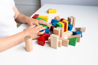 Beyaz bir masada renkli tahta bloklarla oynayan bir çocuk. Yüksek kalite.