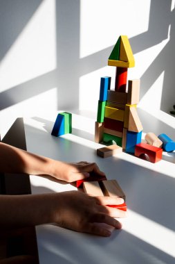 Çocuk elleri masaya renkli ahşap blok kule inşa ediyor. Yüksek kalite.