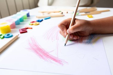 Evde beyaz kağıda renkli kalemler çizen çocuk. Yüksek kalite.