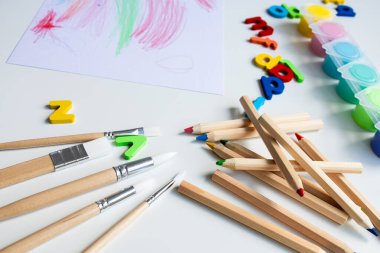 Renkli sanat malzemeleri. Kalemler, fırçalar, boyalar ve alfabe harfleri masanın üzerinde. Yüksek kalite.