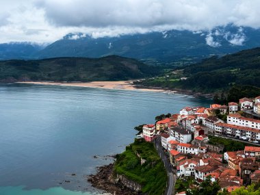 1 Haziran 2025. Lastres, İspanya. Huzurlu körfez ve dağlara bakan kırmızı çatıları olan manzaralı bir sahil köyü. Yüksek kalite.