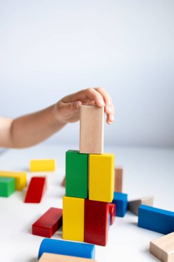 Beyaz yüzeyde renkli tahta blokları istifleyen bir çocuk. Yüksek kalite.