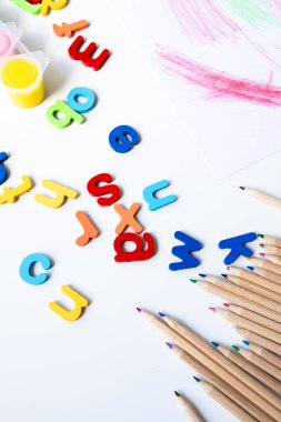 Beyaz arka planda resim malzemeleri ve kalemlerle dolu renkli alfabe harfleri. Yüksek kalite.