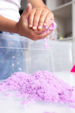 Yaratıcı eğlence için mor kinetik kumla oynayan bir çocuk. Yüksek kalite.