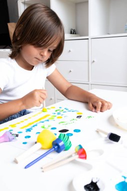 Ev sanatları dersinde pul ve fırçayla resim yapan beyaz bir çocuk. Yüksek kalite.