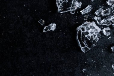 Karanlık yüzeyde yansıtıcı ışık oyunuyla parçalanmış cam parçaları. Yüksek kalite.