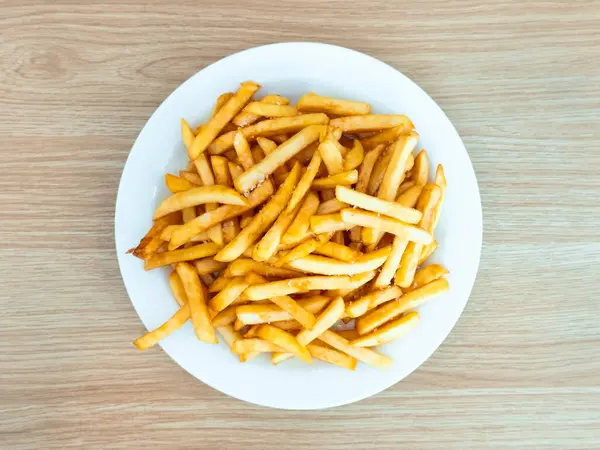 Tahta yüzeyde beyaz tabakta kızarmış patates kızartması. Yüksek kalite.