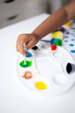 Child painting with palette using cotton swab technique. High quality.