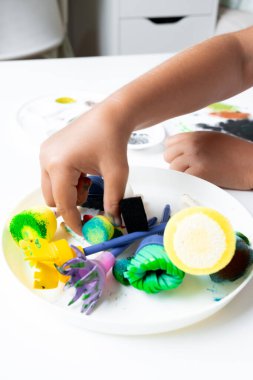 Child engaging in creative art activity with colorful craft tools. High quality.