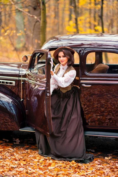秋の背景にレトロな茶色の車の中で座ってベールとヴィンテージドレス レースブラウスと帽子の美しい女性 自然の上にポーズをとる手袋のエレガントな女性暖かい芸術作品 — ストック写真