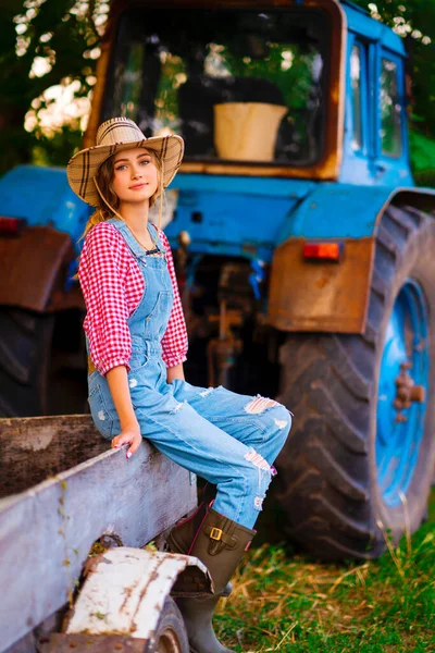 Hasır Şapkalı Kot Pantolonlu Güzel Sarışın Kovboy Kız Traktörün Üzerinde — Stok fotoğraf