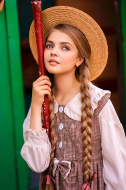 Yeşil trenin yanındaki istasyon platformunda dikilen klasik elbiseli ve hasır şapkalı güzel sarışın kızın portresi. Gülümseyen zarif, mavi gözlü hoş bayan. Gezgin hakkında sanat çalışması.