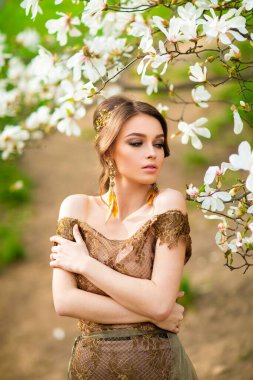 Çiçek açan bahçede dikilen dantelli kahverengi elbiseli güzel romantik kız. Manolya ağaçları arasında genç bir model hayal ediyorum..