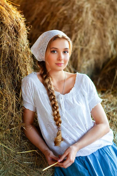 美丽的金发姑娘 留着辫子 穿着白色的乡村衣服 坐在稻草上 农场生活 在牧场上摆姿势的年轻模特 温暖的艺术作品 — 图库照片