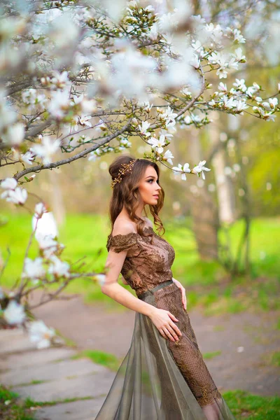 春開花庭に立ってファッション長いレース茶色のドレスで美しいロマンチックな女の子 マグノリアの木の間の若いモデルを夢見て — ストック写真
