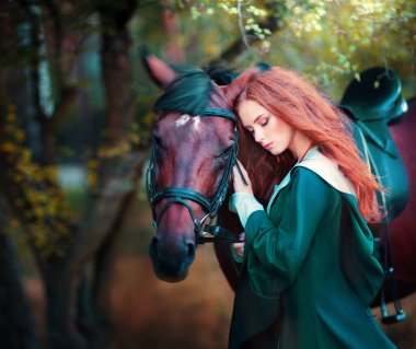 Yeşil ortaçağ elbiseli güzel kızıl saçlı kız atın üstünde oturuyor ve uzaklara bakıyor. Cesur kalpli kadın hakkındaki peri masalı. Sıcak sanat eserleri.