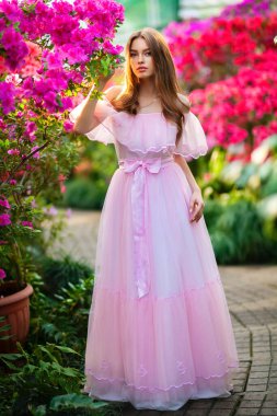 Beautiful  girl in pink  vintage dress and straw hat standing near colorful flowers. Art work of romantic woman .Pretty tenderness model posing and looking at camera. clipart