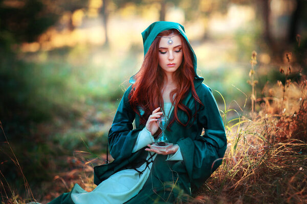 Portrait of a beautiful red haired girl in green medieval dress on glowing sun. Fairy tale story about brave heart woman.Amazing model looking at camera.Warm art work