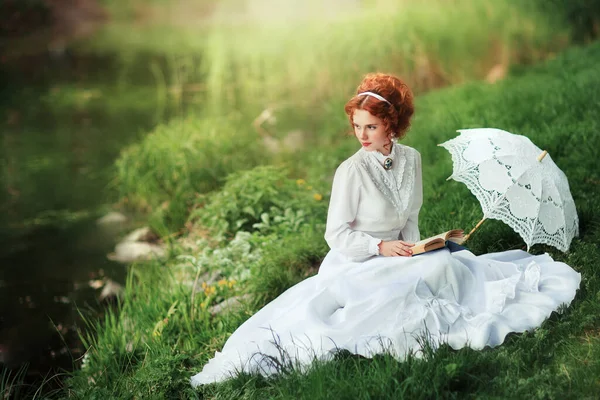 川の近くに立つ白い長いヴィンテージドレスの美しい赤い髪の女の子 レース傘とロマンチックな女性の芸術作品 — ストック写真