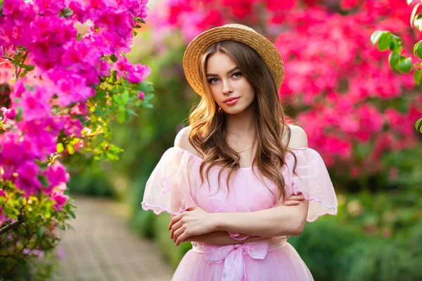 ピンクのヴィンテージドレスとカラフルな花の近くに立っているわらの帽子の美しい女の子 ロマンチックな女性のアート作品かなり優しさモデルポーズとカメラを見て — ストック写真