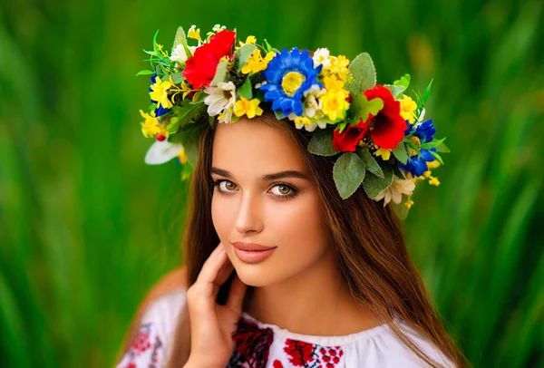 川の近くに緑の自然をポーズウクライナの伝統的なドレスや花輪で美しい長い編組髪の女の子 カラフルな暖かい背景に若い魅力的なスタイリッシュな女性の肖像画 — ストック写真