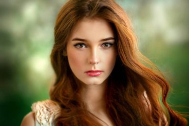 Çiçek açan bahçede duran beyaz dantelli, güzel, kızıl saçlı kız. Kameraya bakan genç bir model.