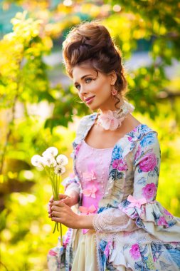 İlkbahar Mükemmel saç stili ile güzel romantik kız yeşil güneşli bahçede duruyor karahindiba ile. Peri masalı gibi giyinmiş rüya kraliçesi. Peri masalı gibi..