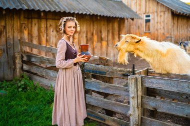 Ortaçağ elbisesi ve şapka takıp çiftlikte poz veren güzel, kırsal bir kız. Kırsal kesimde güzel sarışın bir manken.. 