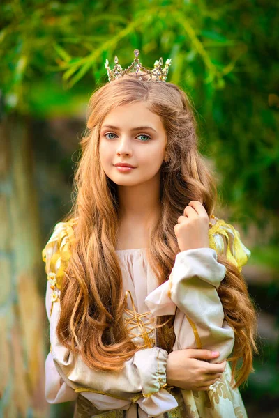 美丽的金发碧眼的公主穿着中世纪金色的衣服 头戴小小的皇冠 漂亮的女王在石碑旁边摆姿势 温暖的艺术作品 — 图库照片