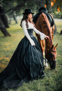 At gezdiren muhteşem moda gotik kız portresi. Fantezi sanat eseri ve peri masalı. Siyah-beyaz elbise ve şapka giymiş esmer model..