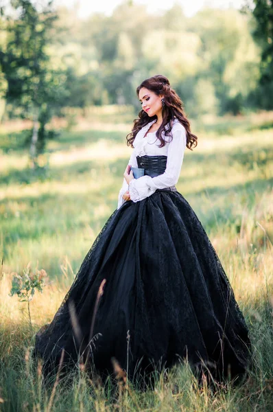 Muhteşem moda gotik kız portresi. Fantezi sanat eserleri. Siyah beyaz elbise ve şapka posteri içindeki esmer model. Genç prenses hakkındaki peri masalı. 