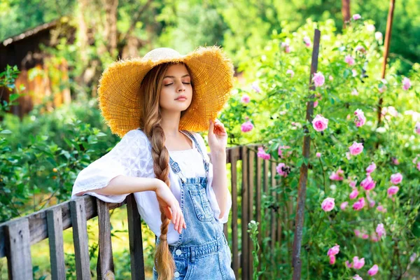 Güzel Örülmüş Sarışın Kız Kot Pantolon Hasır Şapka Giyerek Gül — Stok fotoğraf