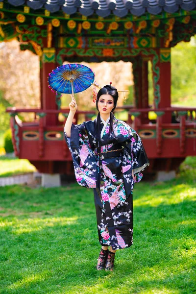 美丽的亚洲黑发女孩 头发缠住 和服摆设在宝塔附近的花圃中 日本年轻模特的春季肖像 — 图库照片