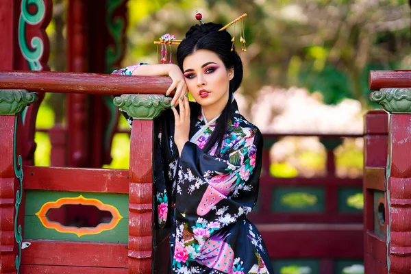머리에 막대기를 기모노 아름다운 아시아 무네트 소녀는 근처의 꽃밭에 모델의 — 스톡 사진