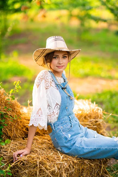 Mooie Blonde Cowgirl Met Strohoed Geruite Overhemd Denim Overall Zittend — Stockfoto