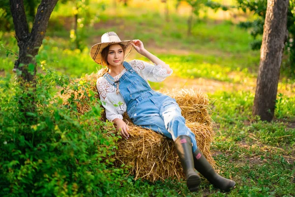Schöne Blonde Cowgirl Mit Strohhut Kariertem Hemd Und Jeans Sitzt — Stockfoto