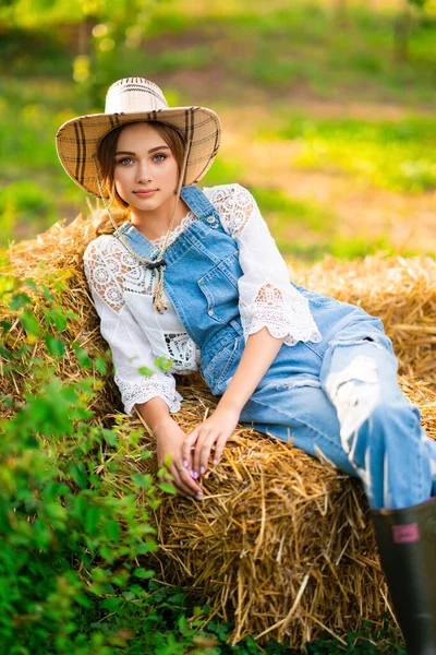 Schöne Blonde Cowgirl Mit Strohhut Kariertem Hemd Und Jeans Sitzt — Stockfoto