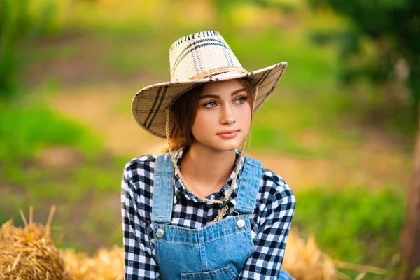 漂亮的金发女牛仔戴着草帽 穿着格子衬衫 头戴绿色背景的草裙 五彩缤纷的艺术作品 — 图库照片