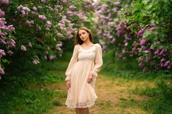 장발에 빈티지 흰옷을 라일락 정원에서 포즈를 취하는 아름다운 자연을 즐기는 — 스톡 사진