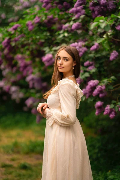 장발에 빈티지 흰옷을 라일락 정원에서 포즈를 취하는 아름다운 자연을 즐기는 — 스톡 사진