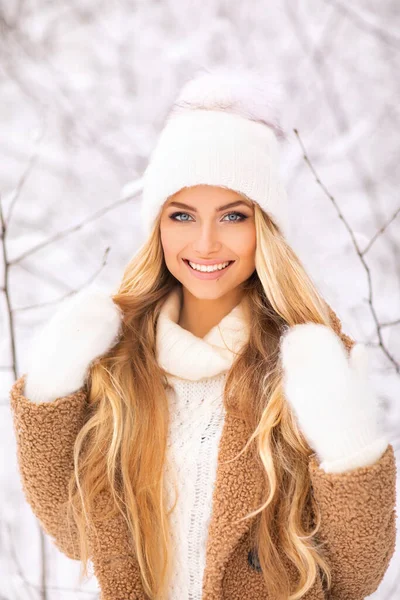 暖かい居心地の良い冬の服で美しい女の子は笑顔でその日を楽しんでいます 白い帽子と明るい輝く冬の日にポーズする手袋の若いブロンドモデル 豪華な女性の肖像画 ウォームアート作品 — ストック写真