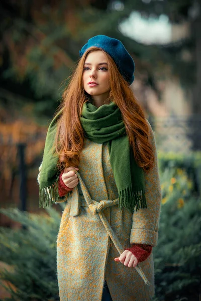 カラフルな背景に立っている緑のスカーフと青い帽子の赤毛の美しい少女の肖像画 秋のロマンチックな女性のアートワーク カメラを見るかわいい優しさモデル — ストック写真
