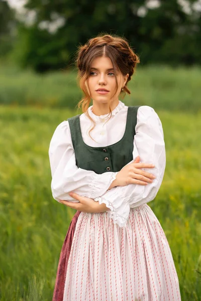 Ortaçağ elbiseli güzel kızıl saçlı kız papatyalarla buğday tarlasında duruyor. Şefkatli, sevimli bir kadınla ilgili peri masalı. Sıcak sanat eserleri..