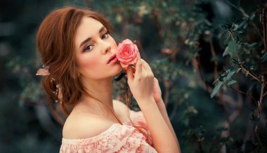 Renkli çiçeklerin yanında duran pembe, eski moda elbiseli güzel kızıl saçlı bir kızın portresini yakından çek. Romantik bir kadının sanat eseri. Kameraya bakan oldukça hassas bir model..