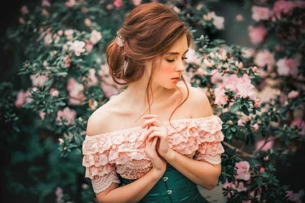 カラフルな花の近くに立っているピンクのヴィンテージのドレスで美しい赤い髪の少女の肖像画を閉じます ロマンチックな女性の芸術作品 見下ろす美しい優しさモデル — ストック写真