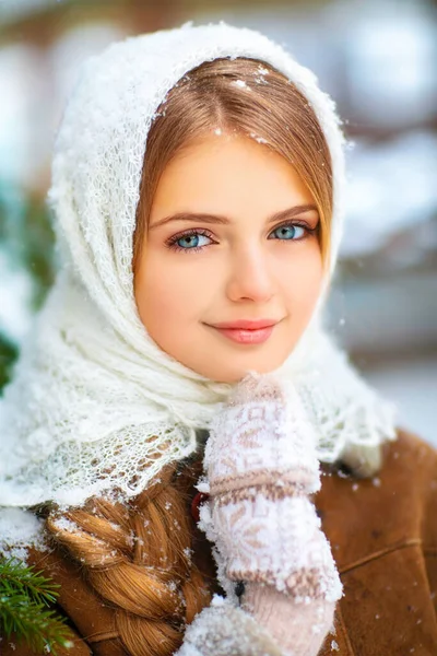 一个长着长长的辫子 蓝眼睛 头戴针织花边围巾 站在木制雪花背景上的年轻漂亮姑娘的冬季画像 — 图库照片