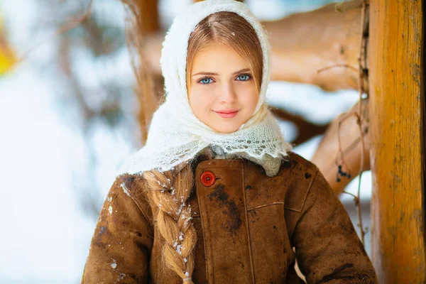 一个长着长长的辫子 蓝眼睛 头戴针织花边围巾 站在木制雪花背景上的年轻漂亮姑娘的冬季画像 — 图库照片